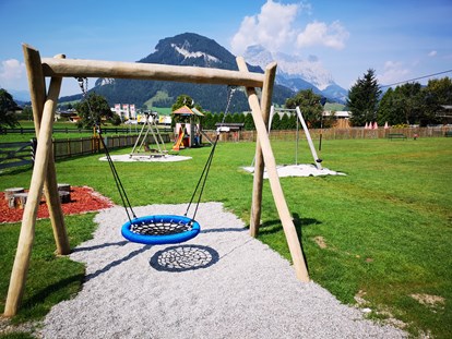 Familienhotel - Kirchdorf in Tirol - Freie Benützung der unmittelbar angrenzenden Spielwiese mit Nestschaukel, Seilrutsche, Spielturm und Trampolin - Hotel babymio