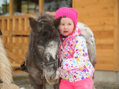Familienhotel - Gosau - Mädchen kuschelt mit dem Pony - Familienhotel Auhof